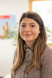 Portraitfoto von einer jungen Frau mit braunen Haaren und braunen Augen trägt eine karierte Bluse.