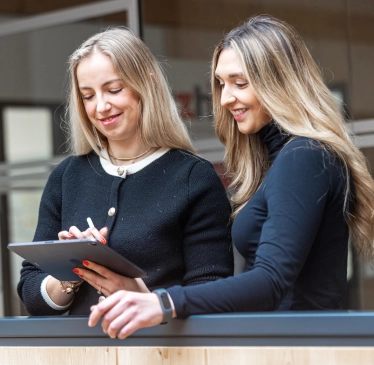 Zwei Frauen schauen gemeinsam auf ein Tablet.