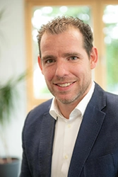 Porträtfoto von dem Herrn Heffels in weißem Hemd und blauen Sakko.