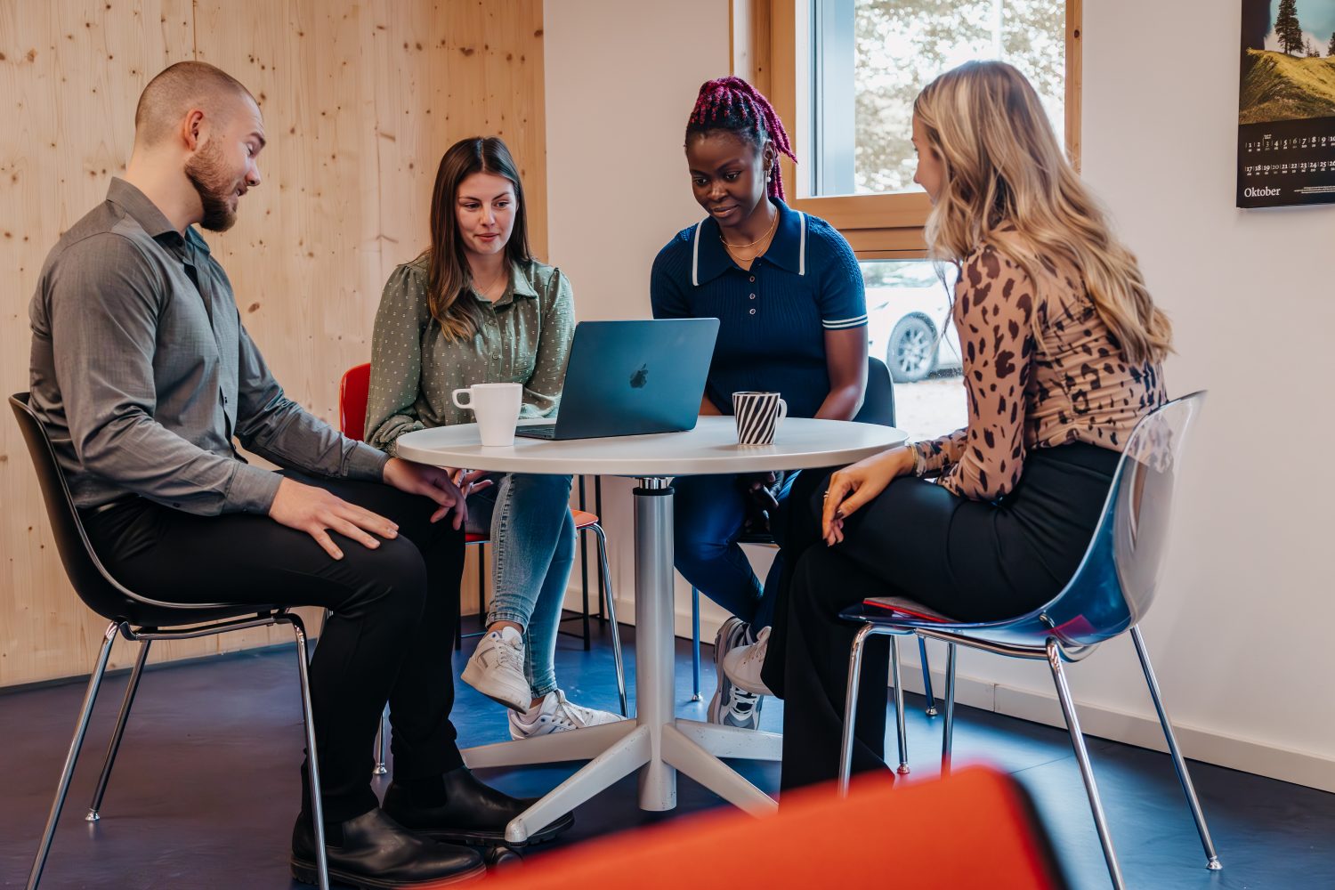 Mitarbeiter sitzen an einem Tisch, auf dem Tisch steht ein Laptop.