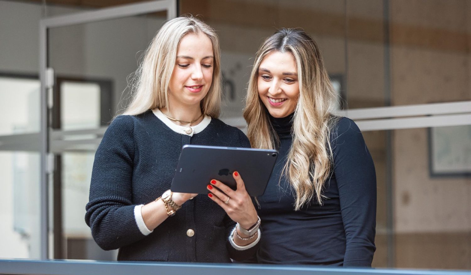Zwei blonde Frauen schauen gemeinsam auf ein Tablet.