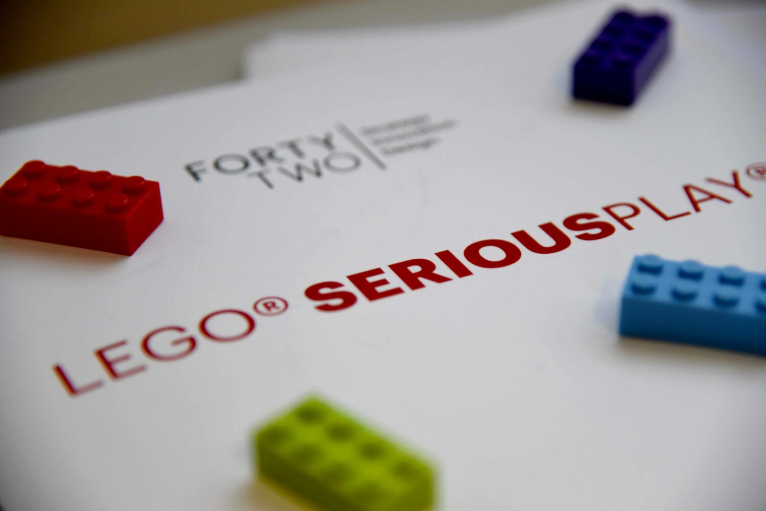 Auf einem Blatt Papier steht Lego serious play und dadrauf liegen bunte Lego-Steine