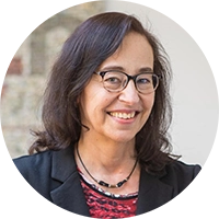 Rundes Bild von einer Frau mit braunen Haaren, Brille, Kette, schwarzem Jackett und rotem Oberteil.