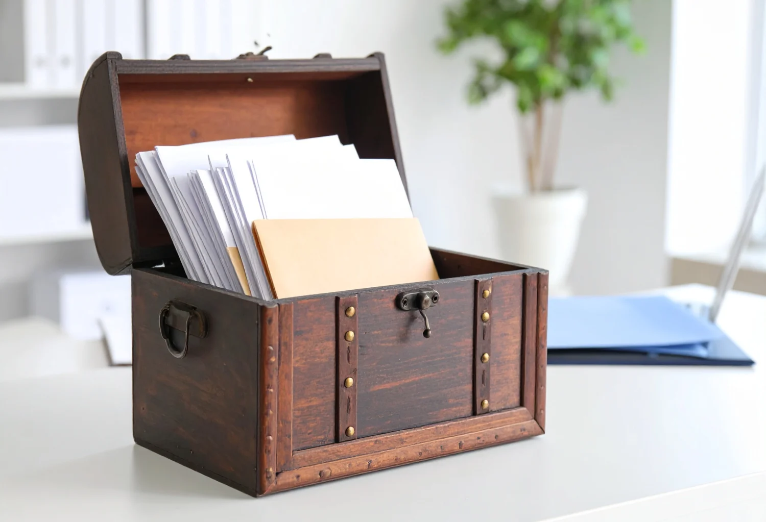 Eine alte Schatzkiste mit Bewerbungsunterlagen steht auf einem weißen Schreibtisch.
